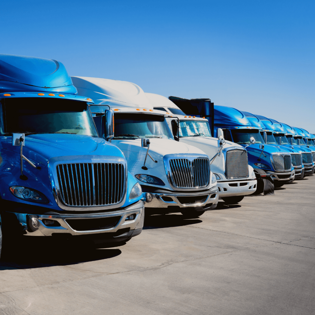 Imagem de uma dianteira de frota de caminhões azuis e brancos, estacionados e alinhados