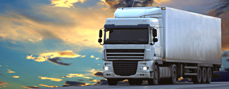 Caminhão de carga em frente de um céu azul com nuvens alaranjadas, representando um veículo em uma frota de caminhões